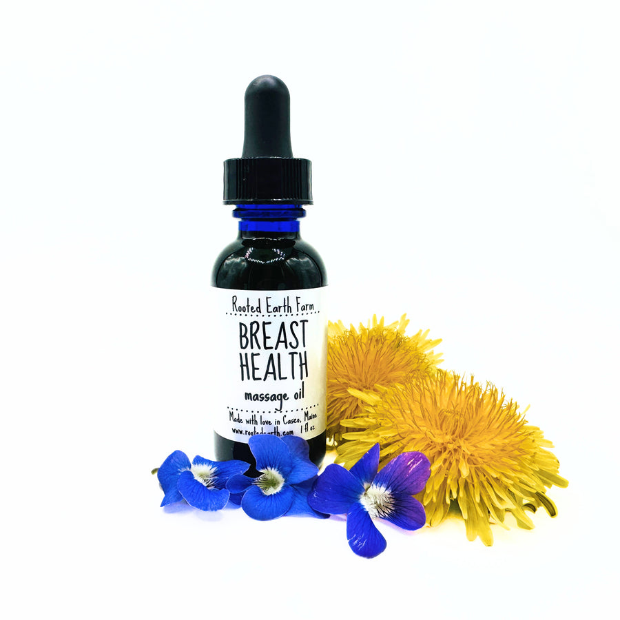 Bottle of Rooted Earth Farm Breast Health massage oil with flowers on a white background. Infused with violets, red clover, and dandelion.